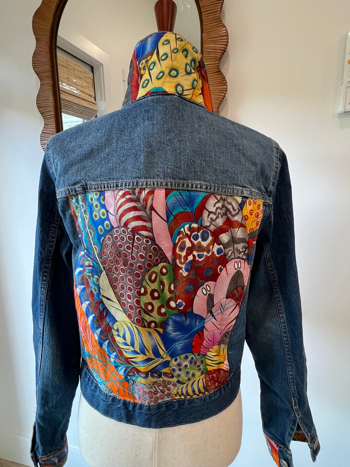 Denim jacket with a colorful feather-print fabric panel